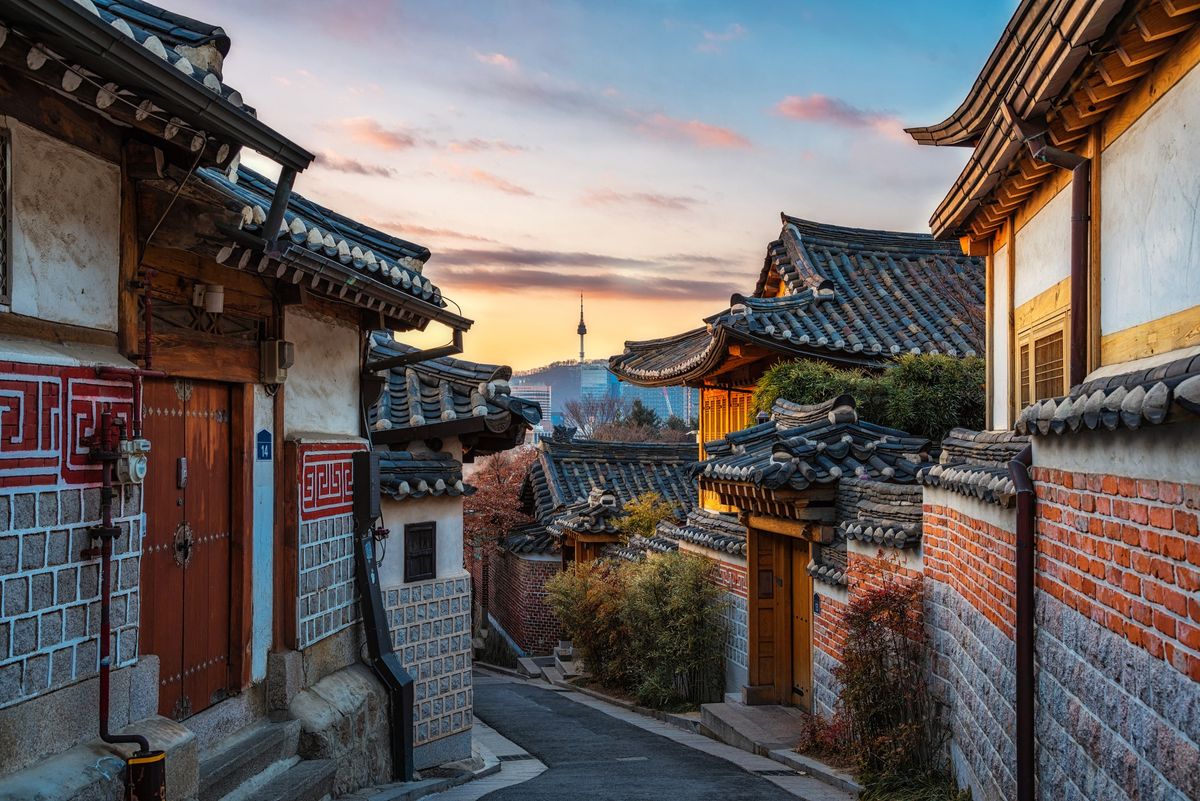 Traditional hanok street in Seoul at sunset, with N Seoul Tower in the distance